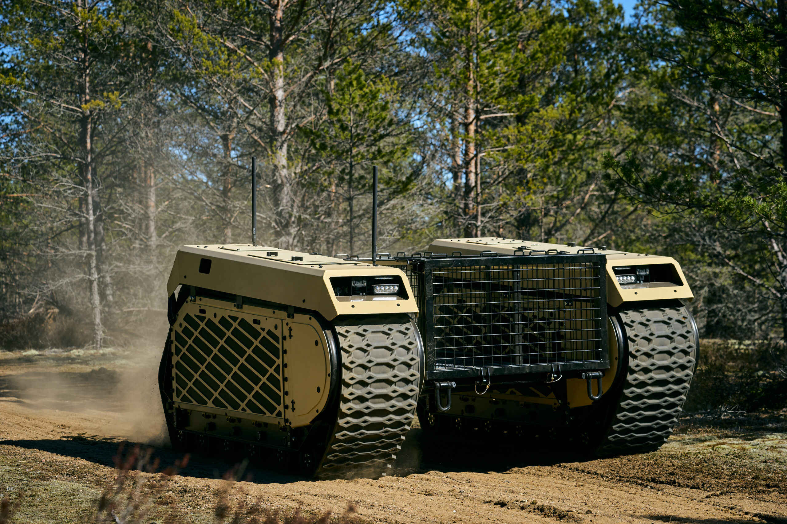 Deux véhicules terrestres sans équipage THeMIS de Milrem Robotics roulant sur un chemin en forêt